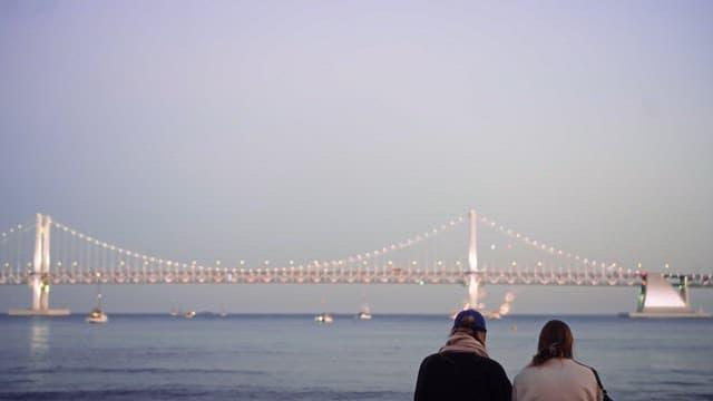 Couple watching illuminated bridge at dusk