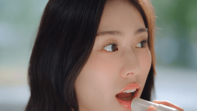 Woman applying lipstick and smiling indoors