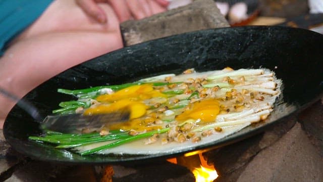 Cooking Korean style pajeon with green onions and fresh clams