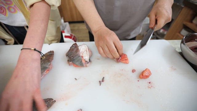 Person cleaning and cutting fish in the kitchen