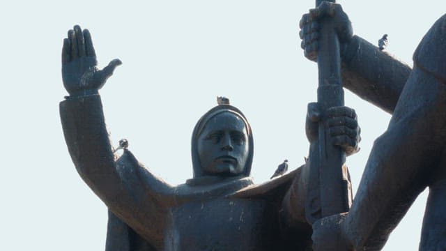 Pigeons resting on a large outdoor statue on a clear day
