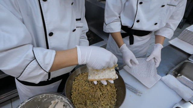 Chef spreading chestnut paste on top of cream-covered bread