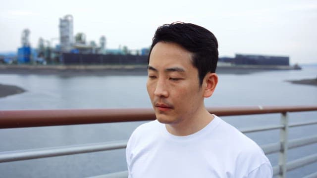 Man walking on a bridge near an industrial area