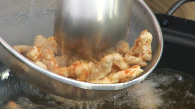 Removing the golden and crispy pork from the oil