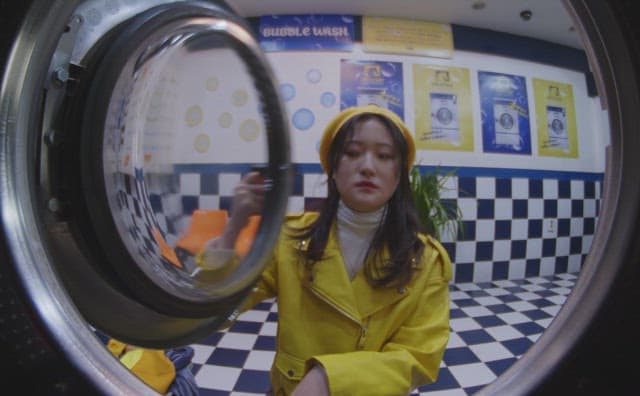 Woman in yellow clothes putting laundry into the washing machine