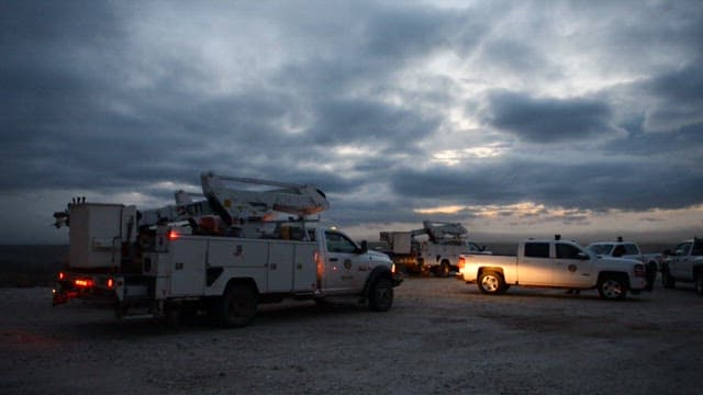 Utility trucks parked under a cloudy evening sky