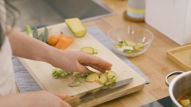 Hand Putting Sliced ​​Zucchini into Soybean Paste Stew