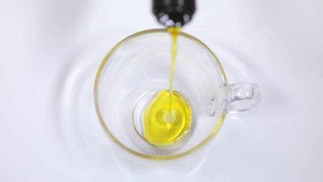 Pouring Hemp Seed Oil into a Glass Cup