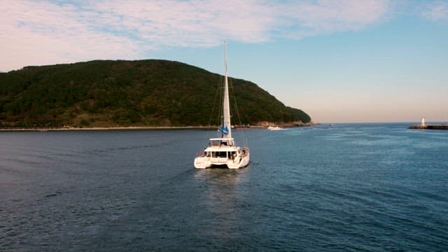 Catamaran Sailing on a Calm Sea near Hills