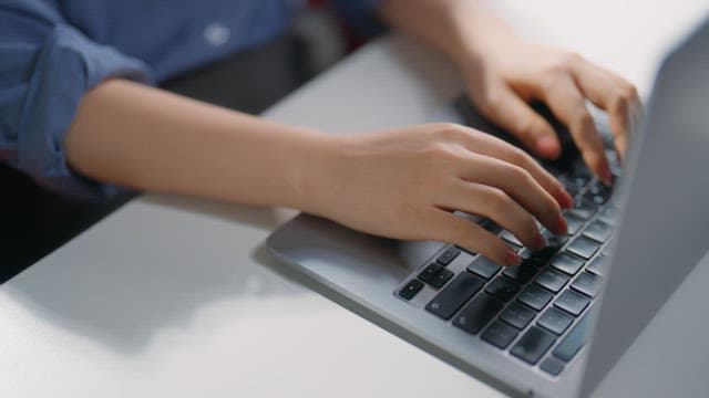 Hands typing on a laptop keyboard
