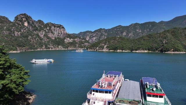 Tranquil Lake with a Boat Passing Between Lush and Majestic Mountains