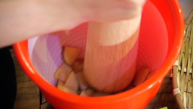 Mashing apple slices with a pestle
