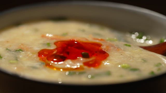 Stirring warm crab meat porridge with chili oil with a wooden spoon