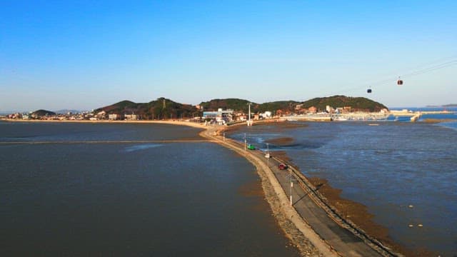 Road on a tidal flat revealed by low tide and cable cars at sunrise