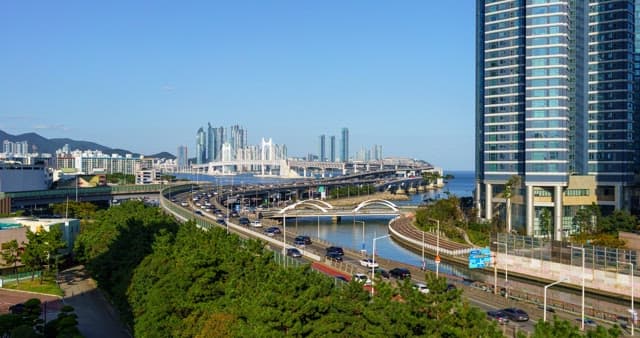 From day to night view of a bustling port city with tall skyscrapers and bridge