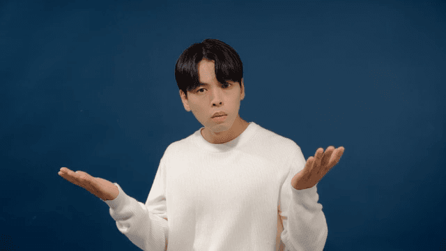 Man in casual white sweater gesturing in confusion