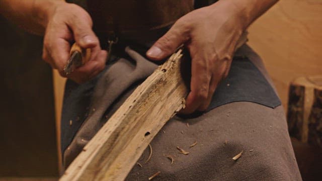 Person carving wood with a knife