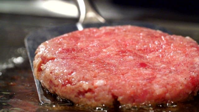 Juicy burger patty sizzling on a grill