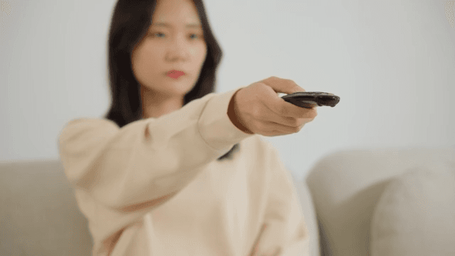 Woman operating a remote control on the sofa