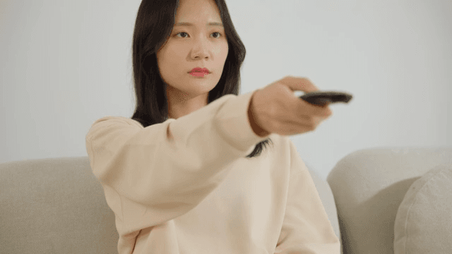 Woman operating a remote control on the sofa