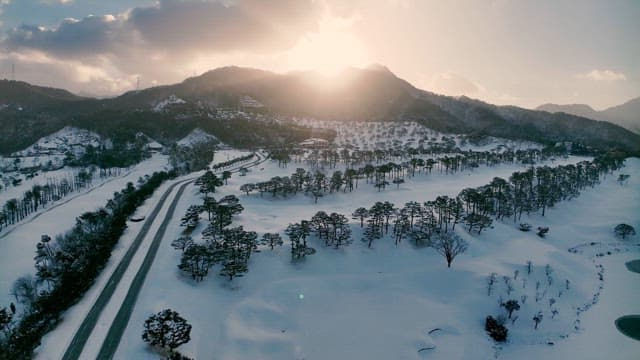 Snowy Landscape with Sun Peeking Through Mountains