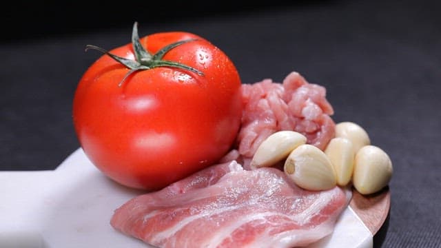 Bowl of stew with fresh tomatoes, pork and garlic