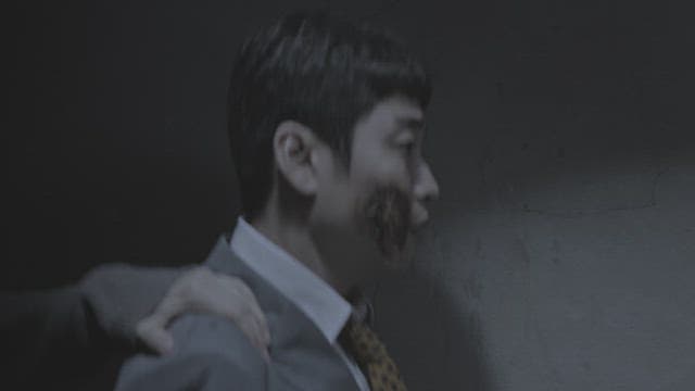 Hand holding the shoulder of a man with a scar on his face