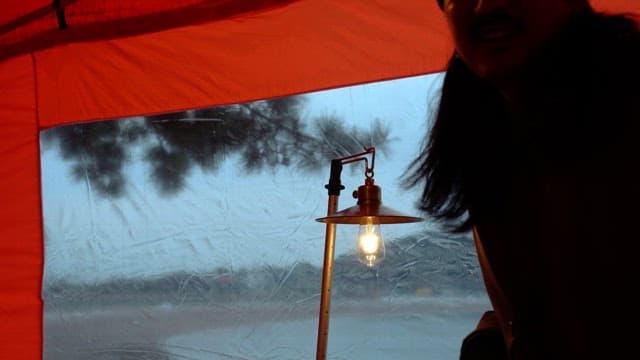 Glowing lamp against the backdrop of a tranquil scene outside the tent