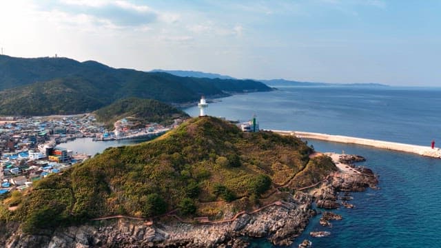 Lighthouse on a coastal hill with a village