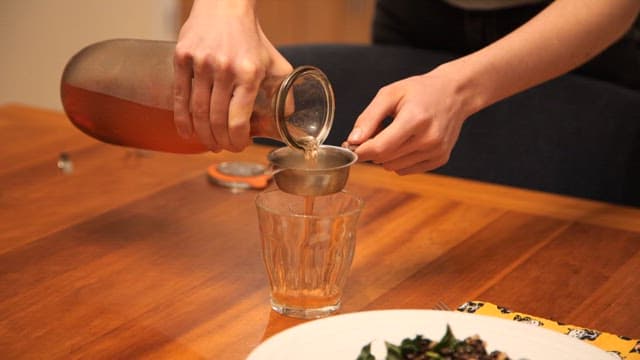 Kombucha being poured in a glass cup on the table