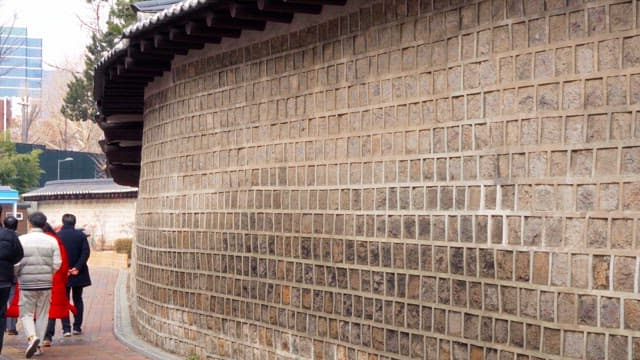 People walking along a traditional Korean wall