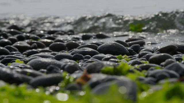 Water waves crashing over pebble stones on the shore