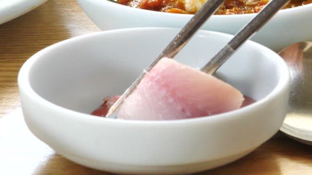 Fresh raw fish dipped in red chili-pepper paste with vinegar at a sushi restaurant