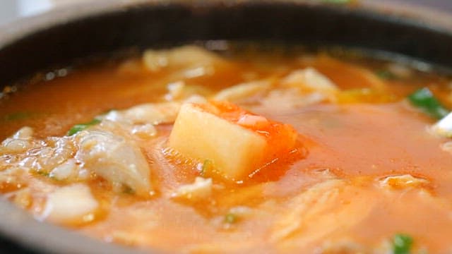 Spoonful of chicken soup with diced radish kimchi