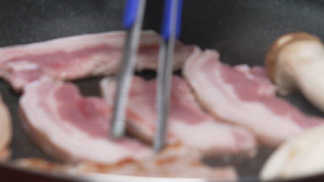 Fresh pork belly being grilled in a hot frying pan