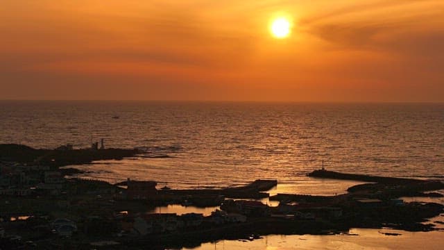 Sunset over a calm ocean with a coastal village