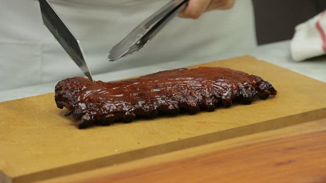 Slicing barbecued ribs on a cutting board