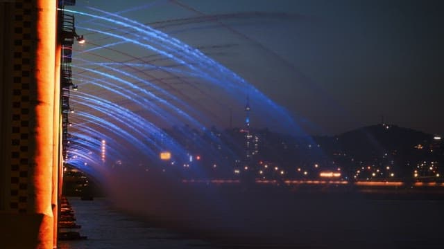 Night view of a bridge with blue water jets in an urban setting