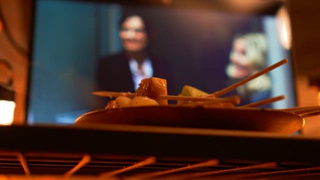 Bowl of skewers arranged on a plate in a wooden table with warm lighting