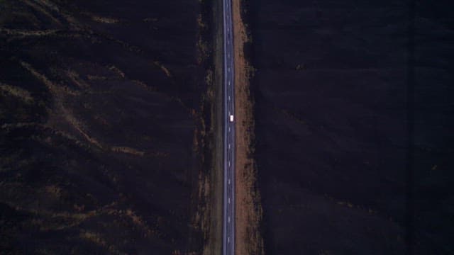 Car traveling on a road through a vast barren landscape