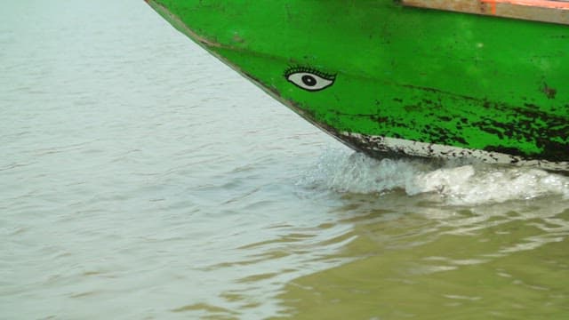 Green boat moving through calm river
