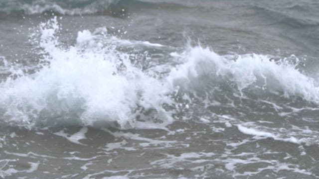 Waves crashing on a shore during a cloudy day