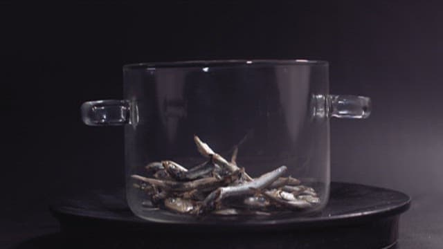 Scene of pouring water into a pot containing dried anchovies