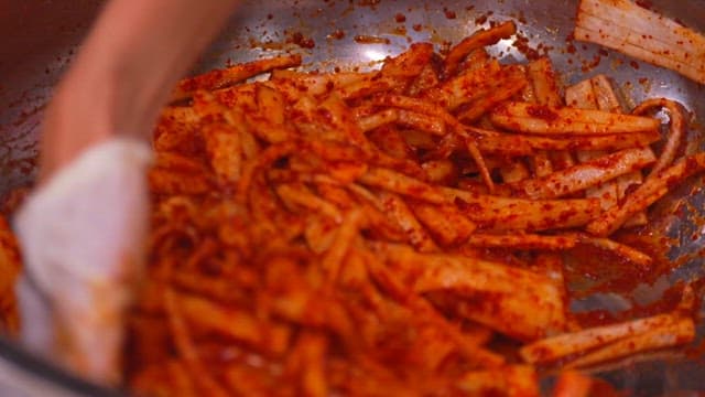 Make the julienne Korean radish salad by mixing the red pepper powder in a large bowl