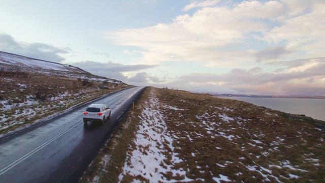 Car driving on a snowy coastal road