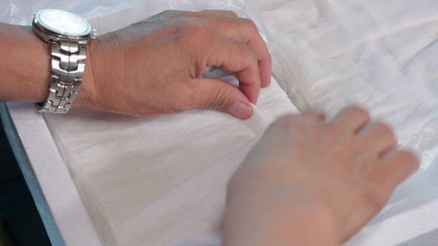 Using a white cotton cloth to remove moisture from tofu