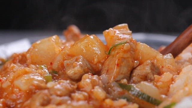 Spoonful of rice bowl with stir-fried radish and pork mixed with a spoon