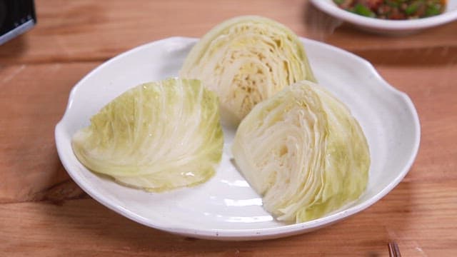 Fresh cabbage slices on a white plate served indoors.