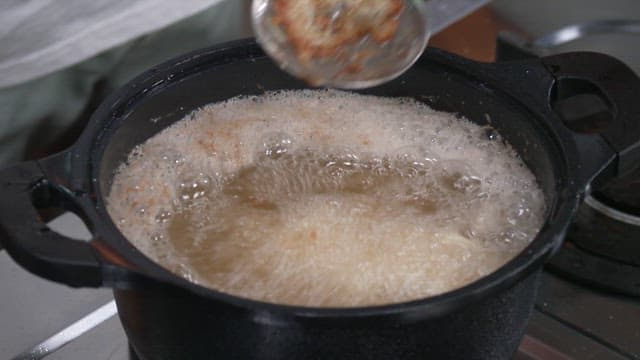 Deep Frying a Flour-covered Onion in Hot Oil