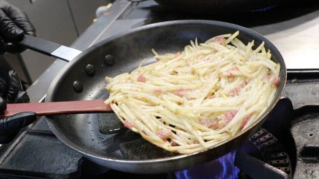 Bacon potato pancakes flipped in a frying pan
